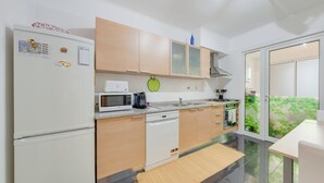 Een moderne keuken met een koelkast, magnetron, koffiezetapparaat en vaatwasser.