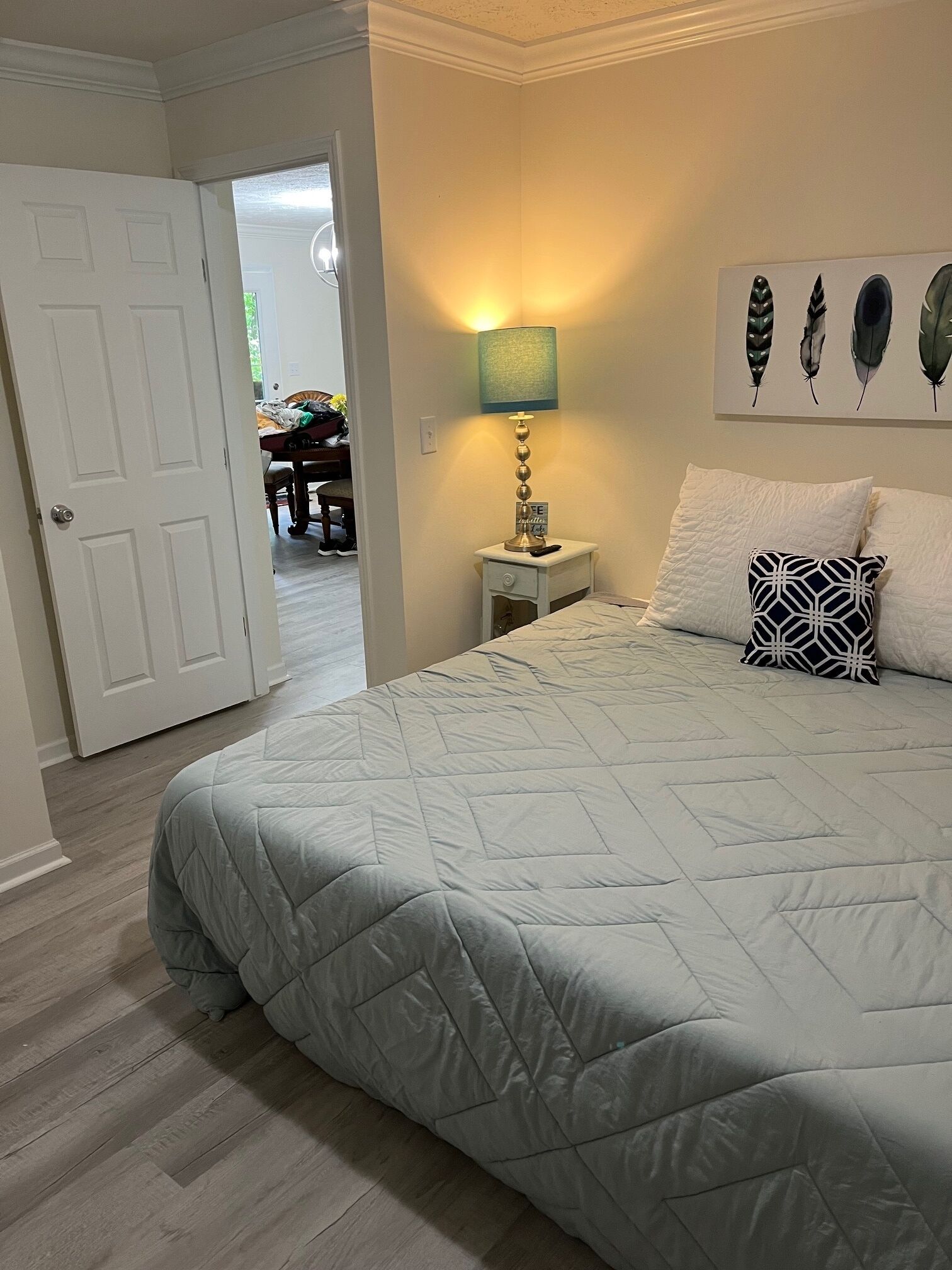 A bedroom with a bed, a nightstand, a lamp, and a wall art piece.