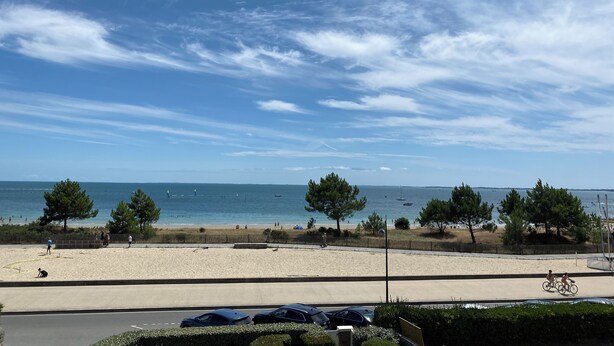 A beach with a clear sky, a sandy shore, and a few people and bicycles.