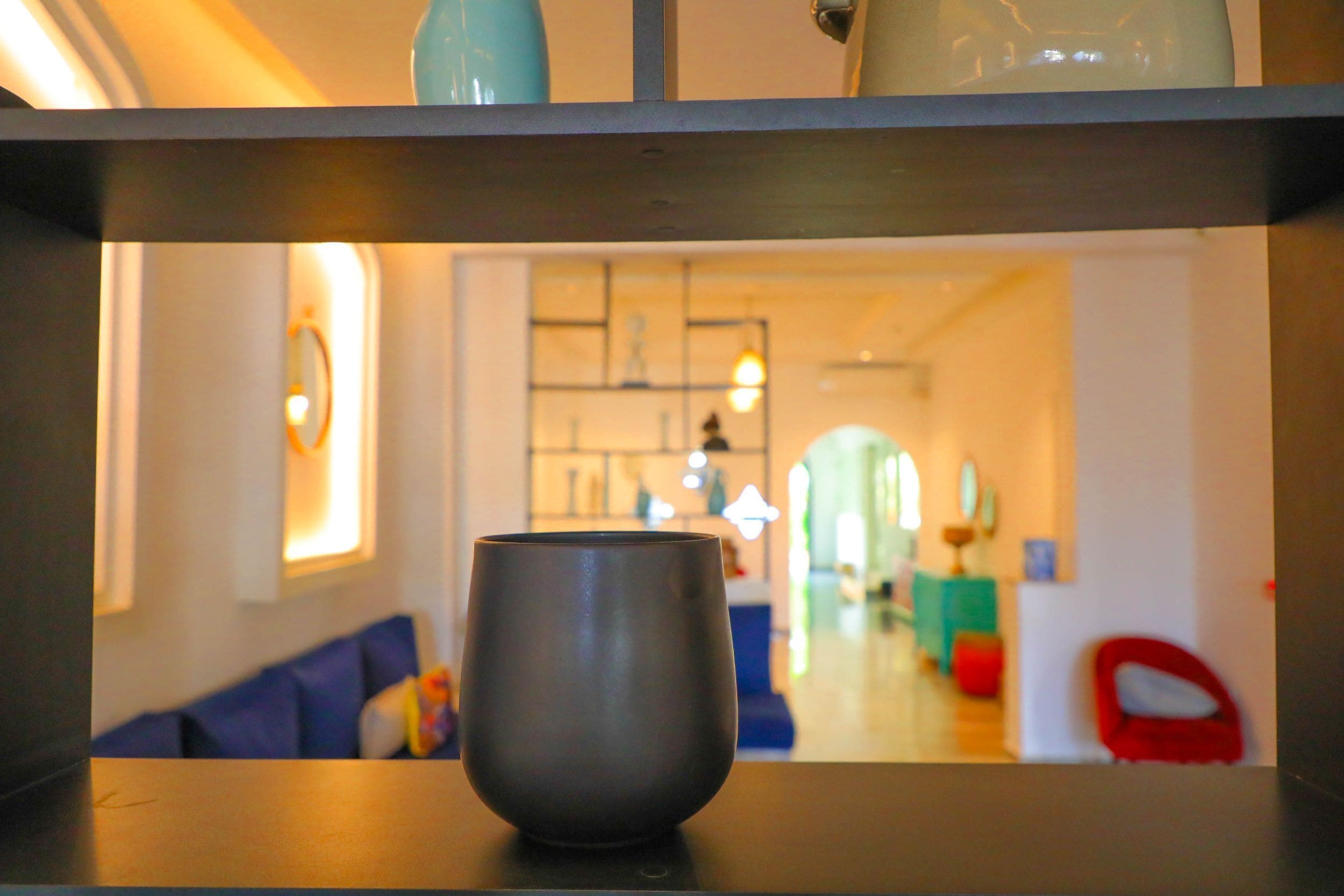 Un salón moderno con una mesa baja oscura en primer plano, un sofá azul y una silla roja al fondo.