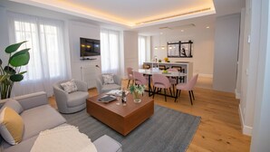 A modern living room with a sofa, coffee table, and dining area with chairs.