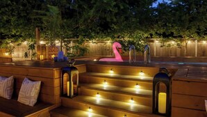 A wooden outdoor seating area with steps, a pink flamingo sculpture, and lanterns. - 6 Bedroom Villa | Pool | Hot Tub Cabana (Austin)