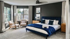 A modern bedroom with a large bed, two bedside tables, a chair, and a desk. - 6 Bedroom Villa | Pool | Hot Tub Cabana (Austin)