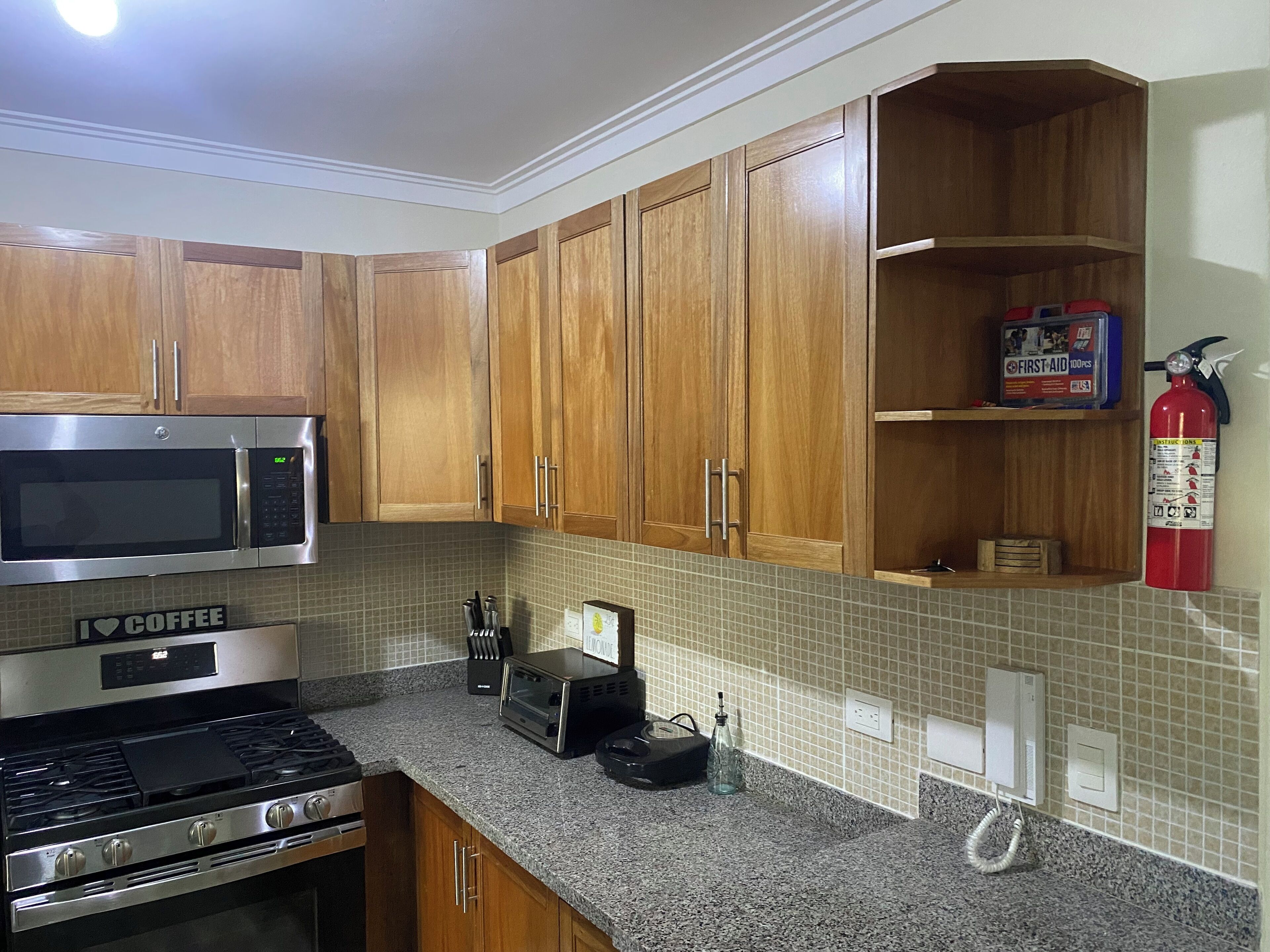 A kitchen with wooden cabinets, a microwave, a stove, and a toaster.