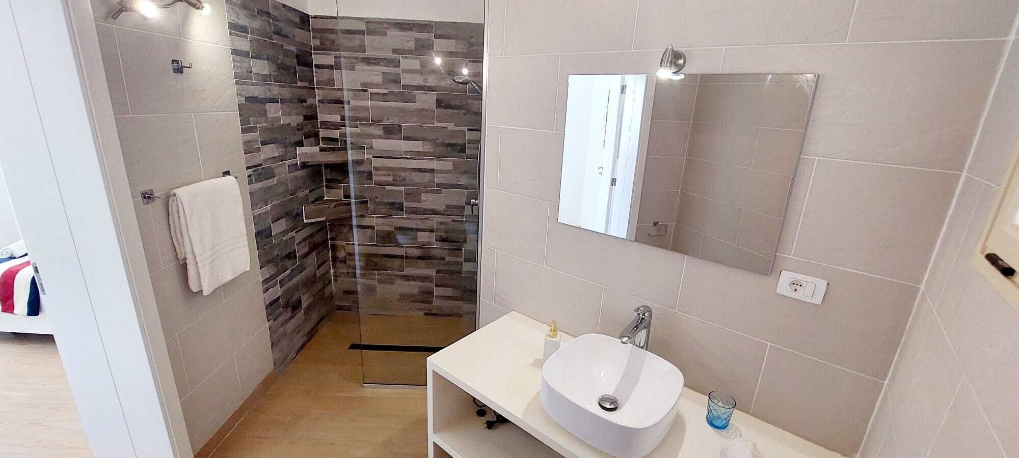 A modern bathroom with a shower, a sink, and a mirror.