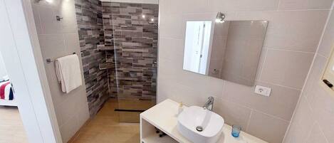 A modern bathroom with a shower, a sink, and a mirror.