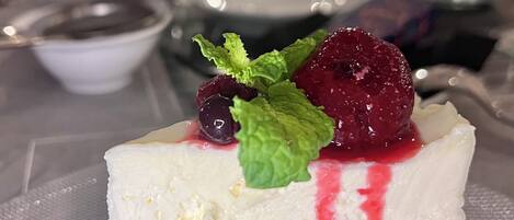 A slice of cheesecake with berries and mint on a plate.
