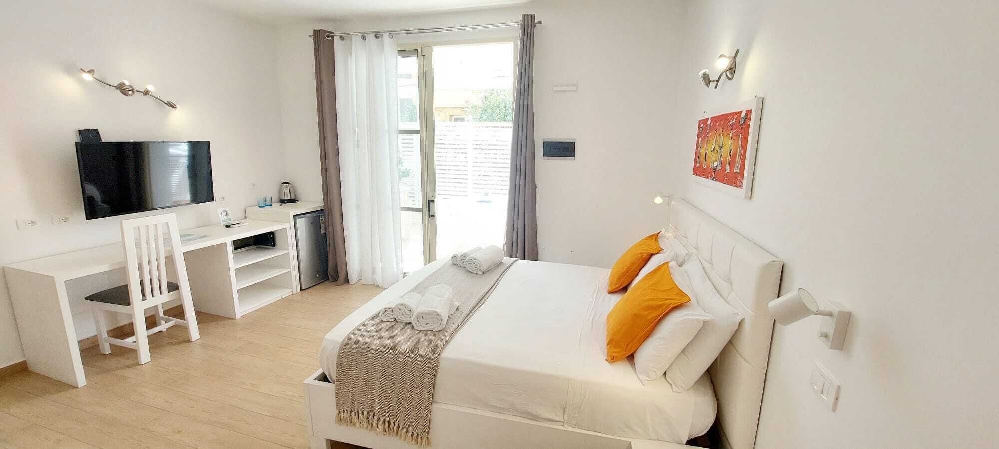 A hotel room with a bed, a desk, a television, and a window with curtains.