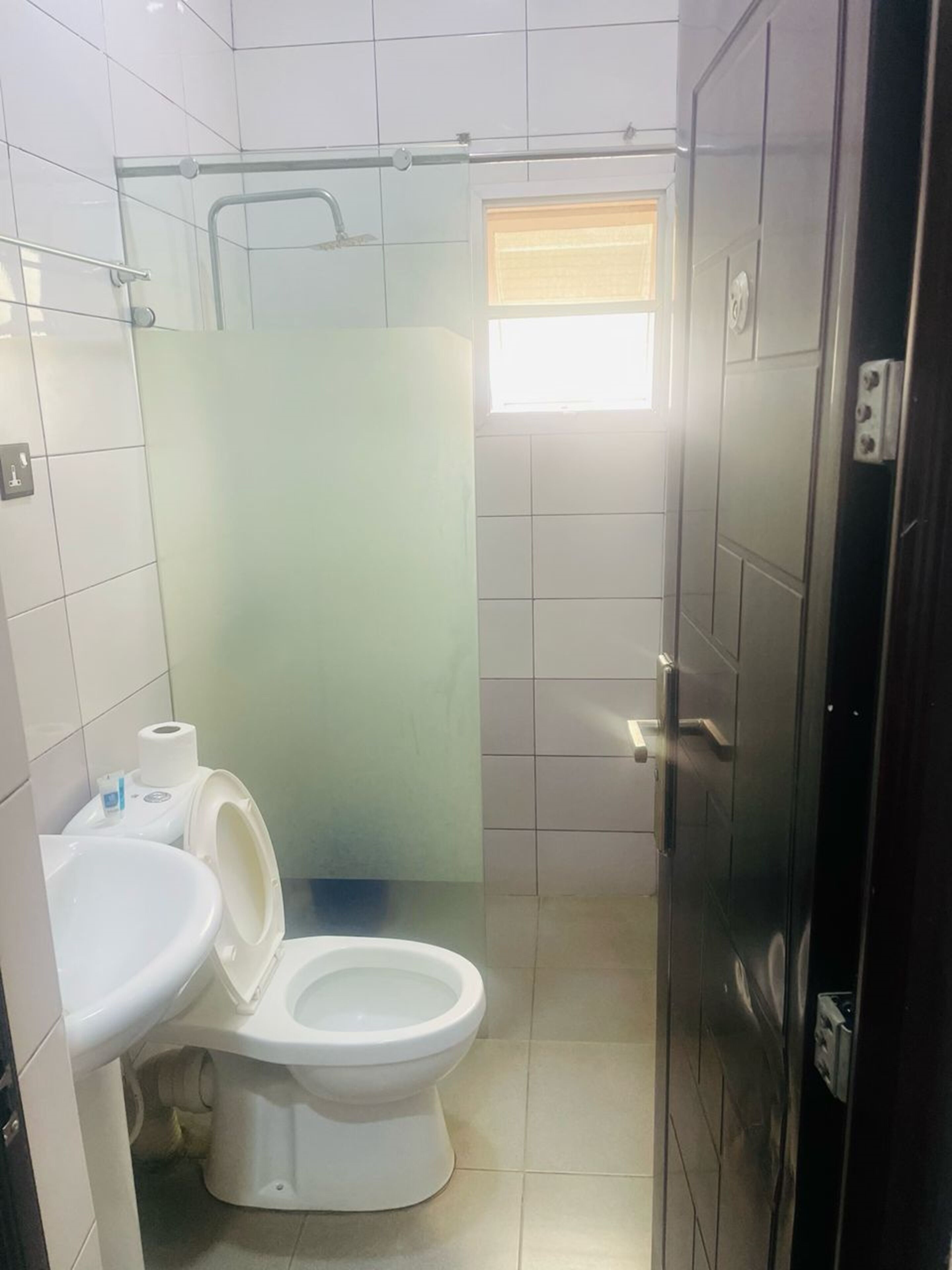 Un baño pequeño con azulejos, un inodoro, un lavabo y una zona de ducha.