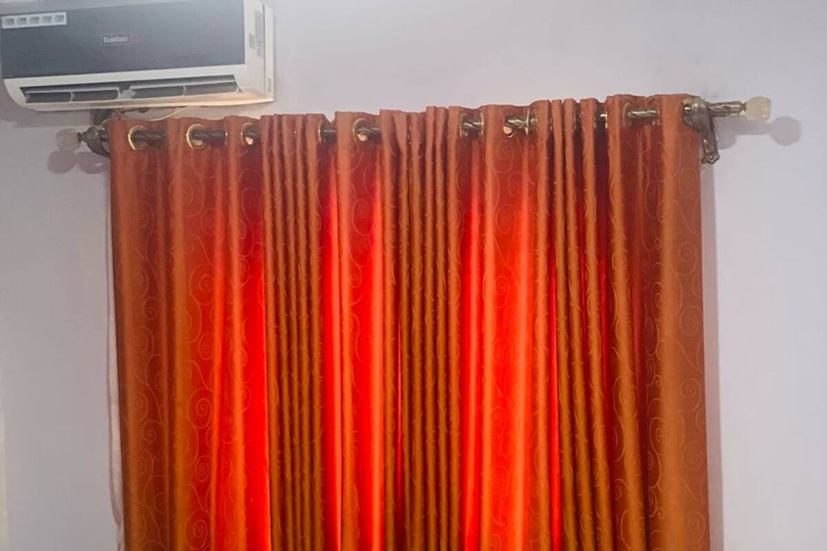 A room with a bed, a curtain, and an air conditioning unit.
