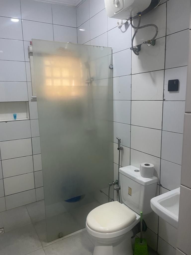 Un baño con cabina de ducha de vidrio, inodoro y lavamanos.