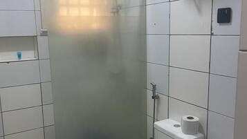 Un baño con cabina de ducha de vidrio, inodoro y lavamanos.
