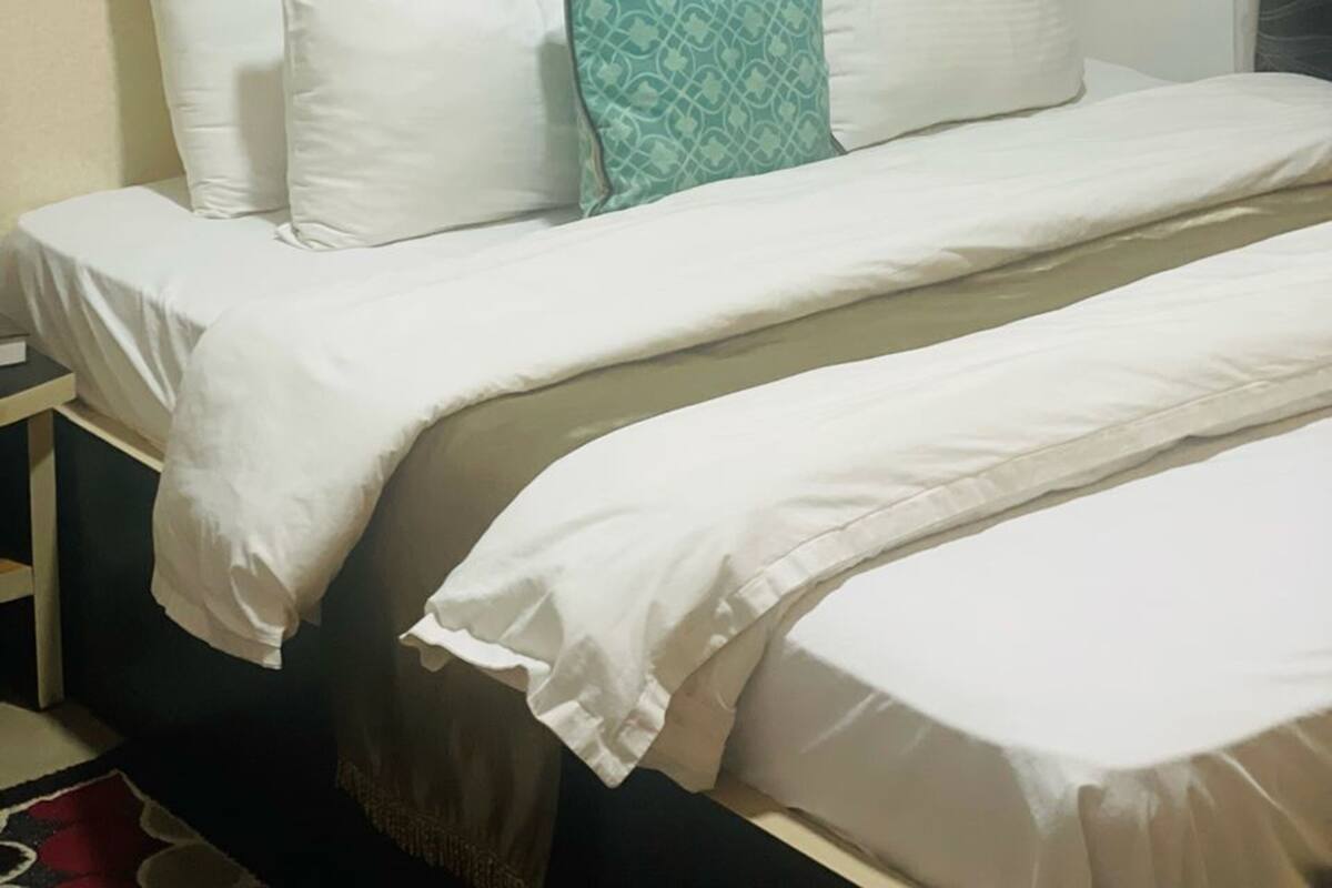 A hotel room with a bed, a nightstand, and a window with a curtain.