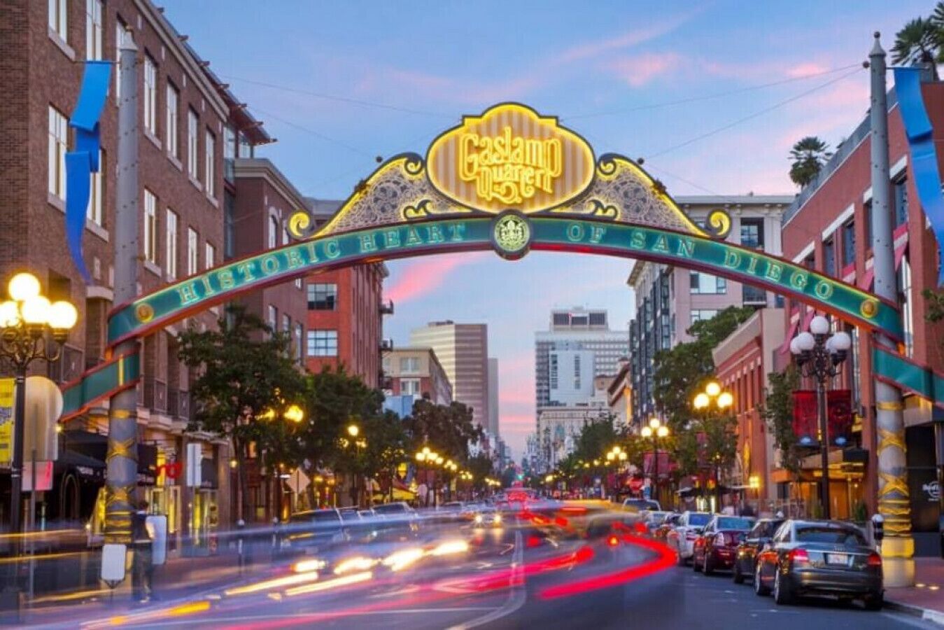 A street view with a historic sign arching over the road, indicating a landmark in San Diego.