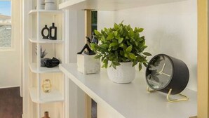 Een modern interieur met witte planken, een plant in pot en een zwarte klok.