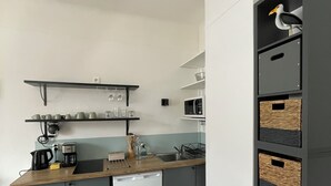 A compact kitchen with grey cabinets, a white dishwasher, and a wooden countertop. - L'escale, Appartement au Cœur de Granville (Granville)