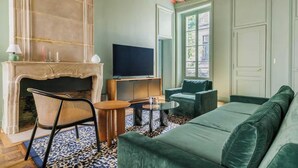 Una sala de estar con chimenea, televisión, sofá y sillón.