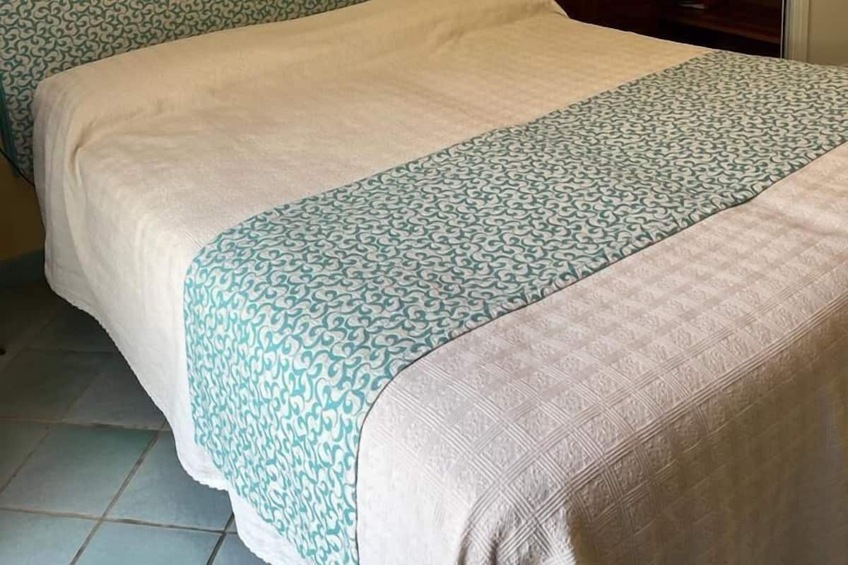 A bedroom with a bed, a nightstand, a wardrobe, and a window with a curtain.