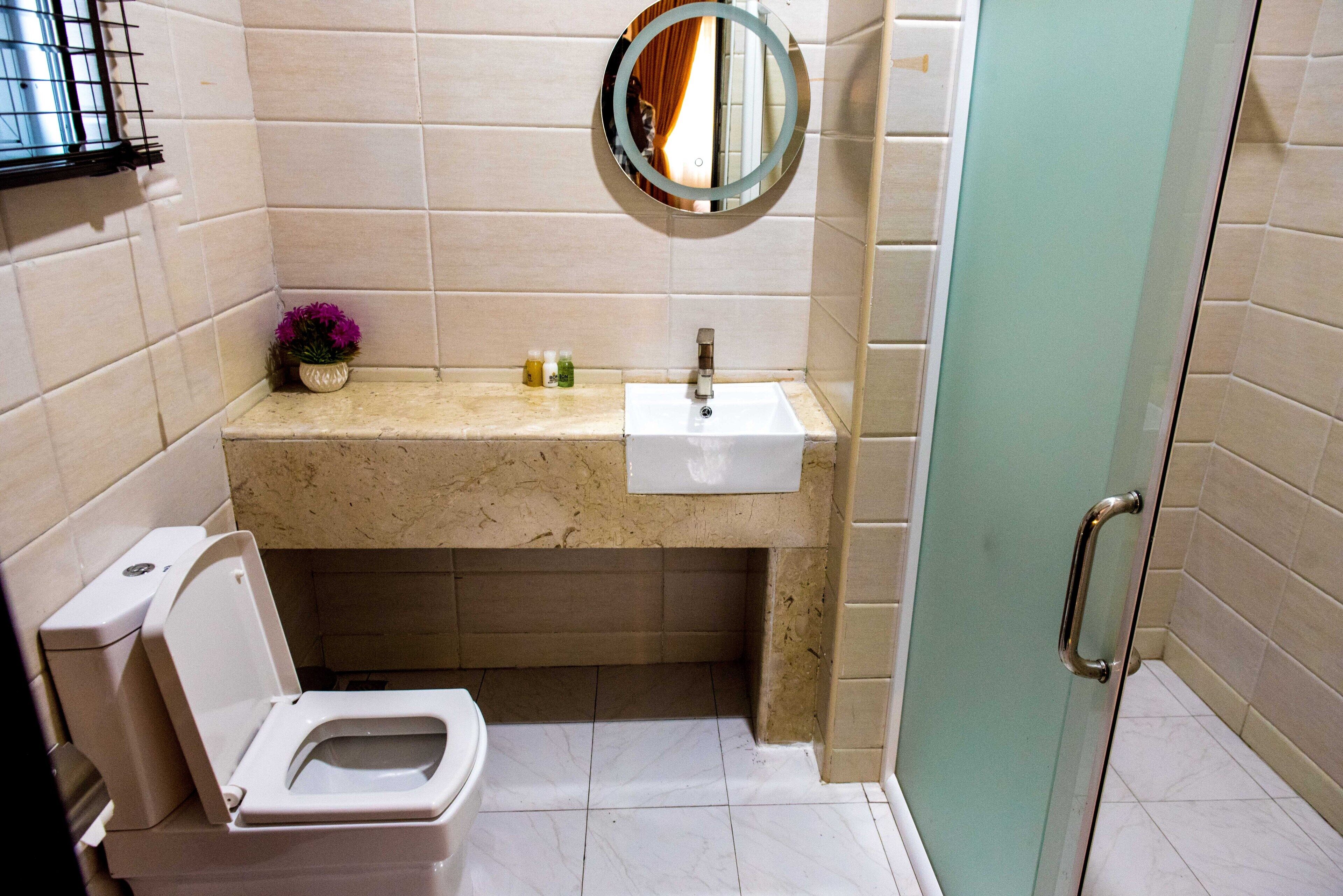 A bathroom with a toilet, sink, and mirror.