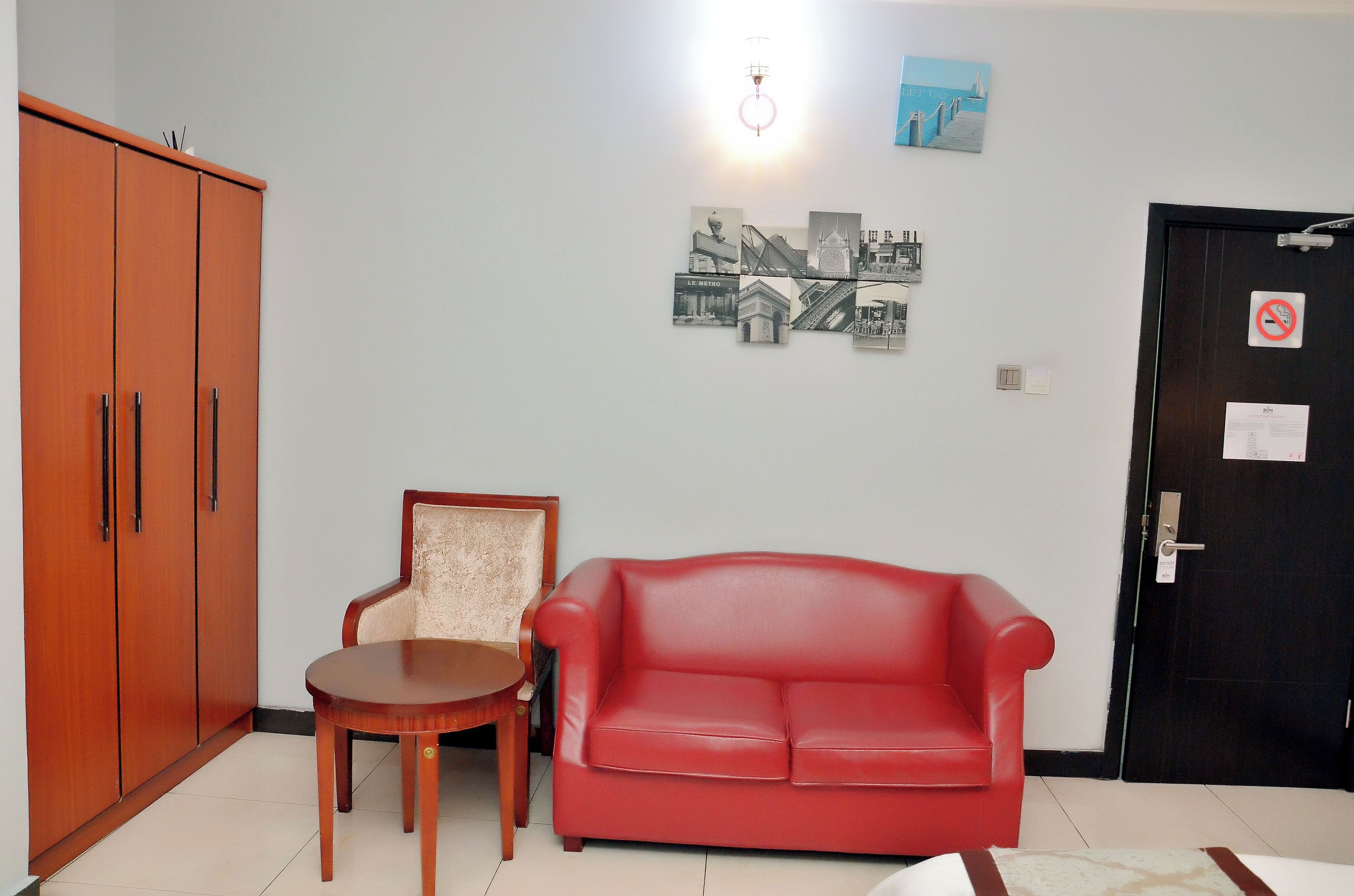 A room with a red leather sofa, a wooden chair, a small wooden table, and a wardrobe.