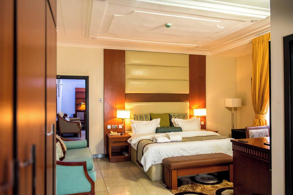 Une chambre d’hôtel avec un grand lit, deux tables de chevet, un bureau, une chaise et un canapé.