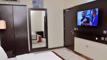 A hotel room with a bed, a TV mounted on the wall, a wardrobe, and a mirror.