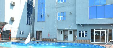 A swimming pool with a flagpole, surrounded by a tiled patio.