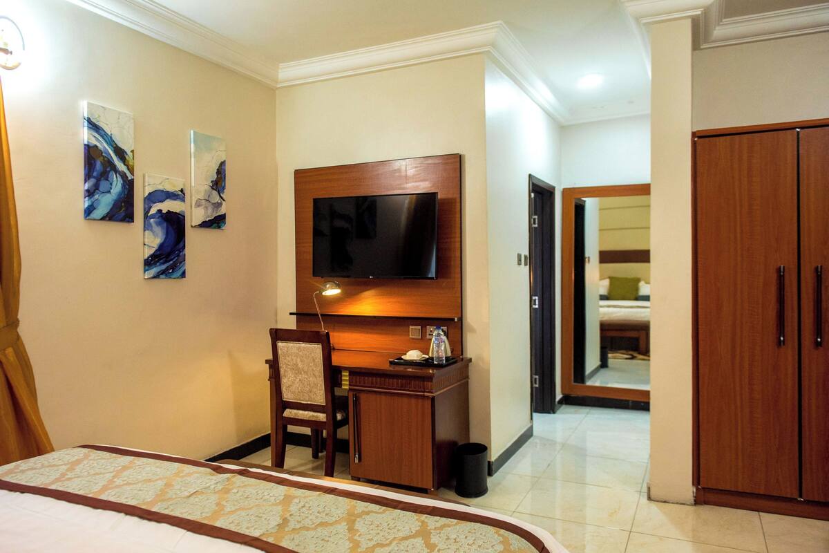Une chambre d’hôtel comprenant un lit, un bureau avec une chaise, une télévision et des œuvres d’art accrochées au mur.