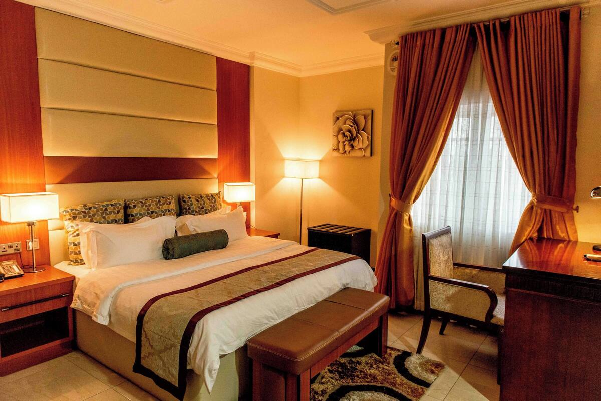 Une chambre d’hôtel avec un grand lit, des lampes de chevet, un bureau et une chaise.