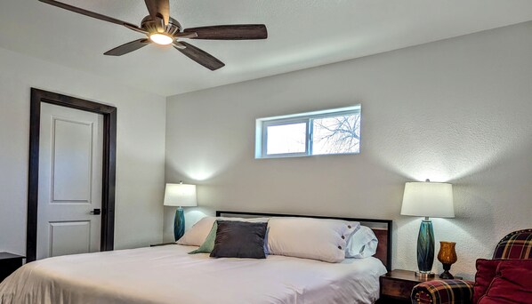 A bedroom with a bed, a ceiling fan, a window, and two bedside lamps. - 5th Street Retreat, quiet townhome a short walk from the heart of Loveland (Loveland)