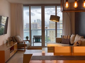 Relax in this stylish living room with a sofa set, coffee table, and side table, and step out onto the balcony for a view of the city and water.