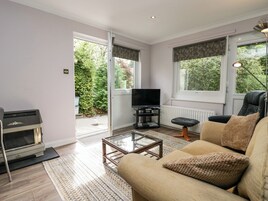 A modern living room with a sofa, a coffee table, a television on a stand, and a fireplace.