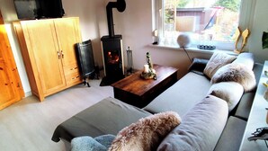 Una sala de estar acogedora con un sofá, un mueble de madera, un televisor, una chimenea y un ventanal con vistas al exterior.