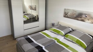 A bedroom with a bed, a wardrobe, a mirror, and a wall-mounted artwork.