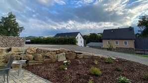 A residential area with stone walls, a paved patio, and a garden with mulch and plants.