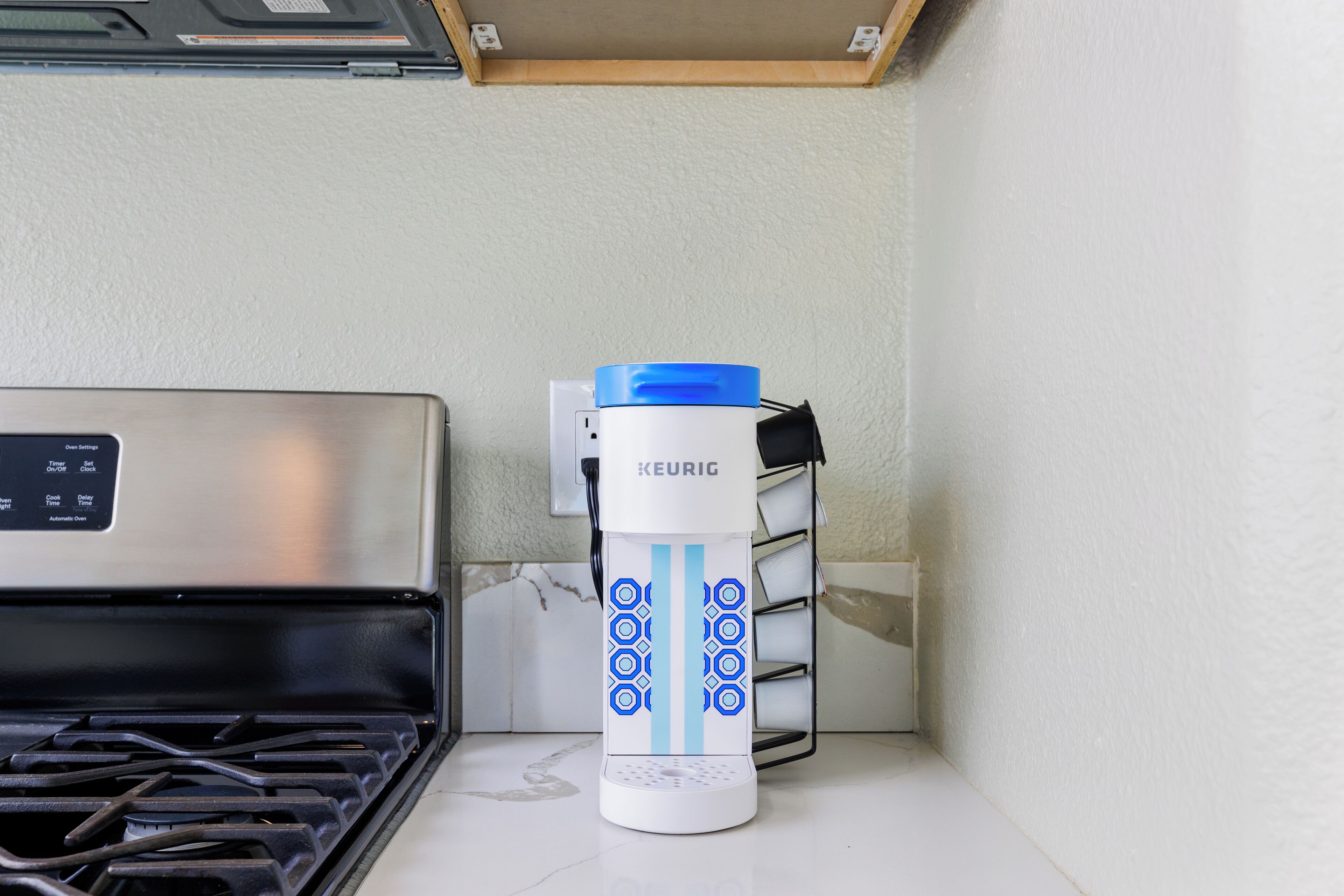 A Keurig coffee maker on a countertop next to a stove.