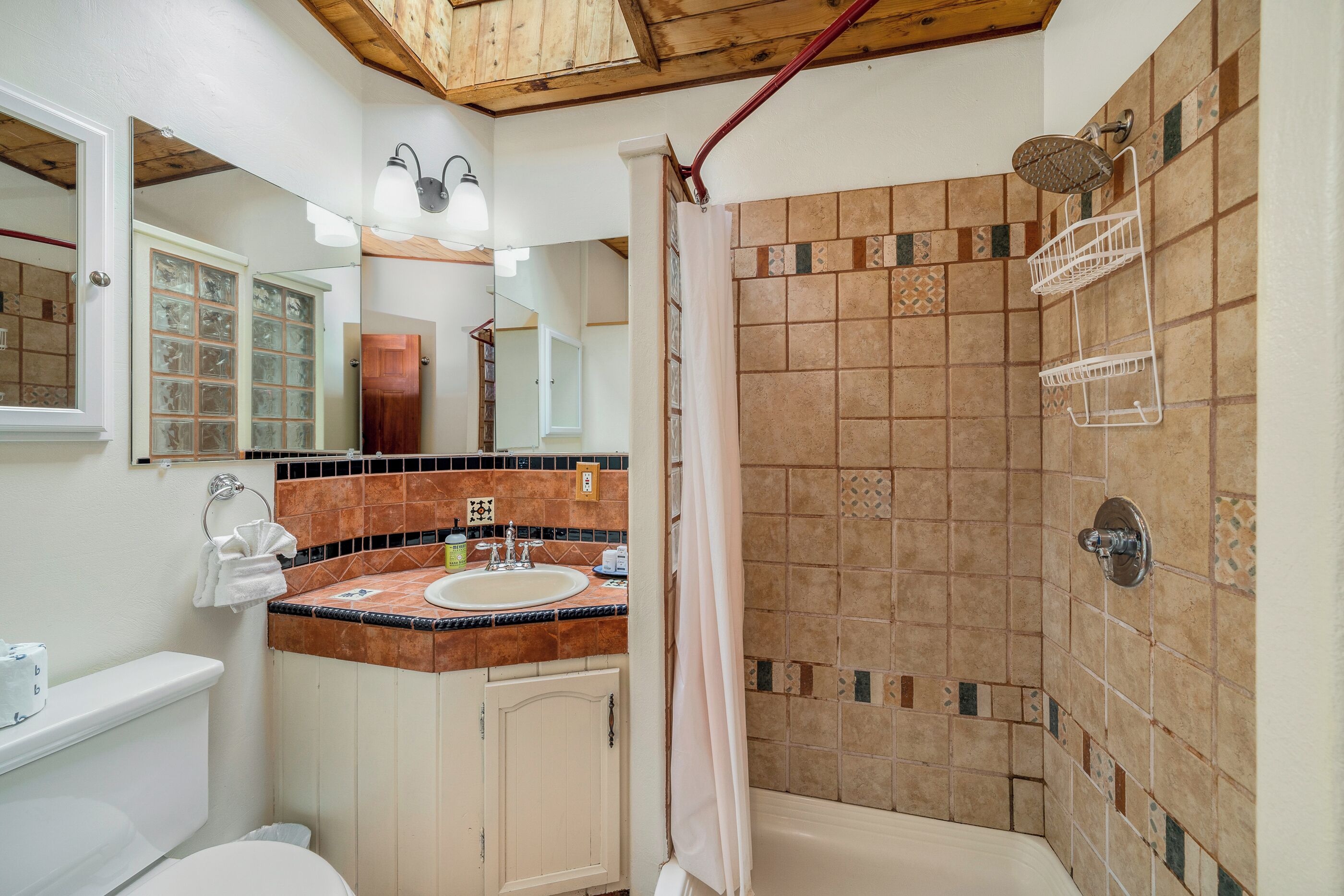 A bathroom with a shower, toilet, sink, and vanity.