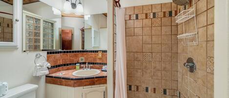 A bathroom with a shower, toilet, sink, and vanity.