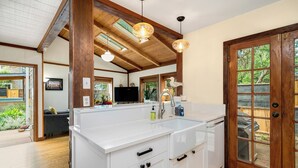 Une cuisine moderne avec des meubles blancs, un grand îlot central et des poutres en bois au plafond.