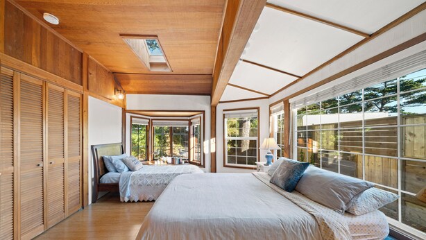 Une chambre avec un grand lit, une armoire en bois et une vue sur l’extérieur.