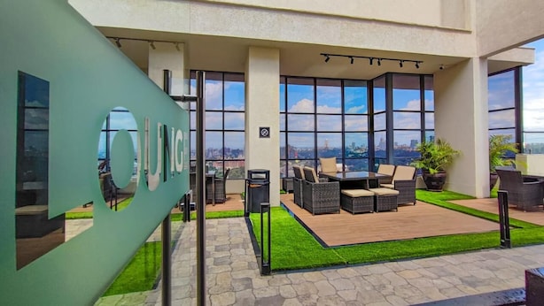 Une terrasse sur le toit avec des sièges extérieurs, une vue sur la ville et une enseigne portant le mot « UNO ».