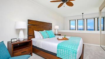 A bedroom with a wooden bed, two nightstands, a ceiling fan, and a large window with a view.