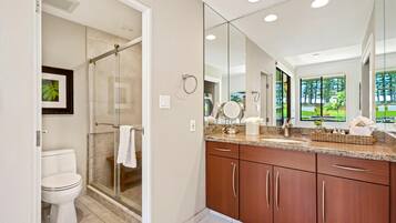 A modern bathroom with a glass shower, a white toilet, wooden cabinets, and a large mirror.
