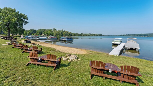 Un cadre idyllique au bord du lac, avec des chaises en bois et une jetée où sont amarrés des bateaux.