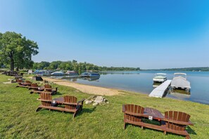 A lakeside setting with wooden chairs and a dock with boats. - Delavan Retreat w/ Patio on Turtle Lake! (Delavan)
