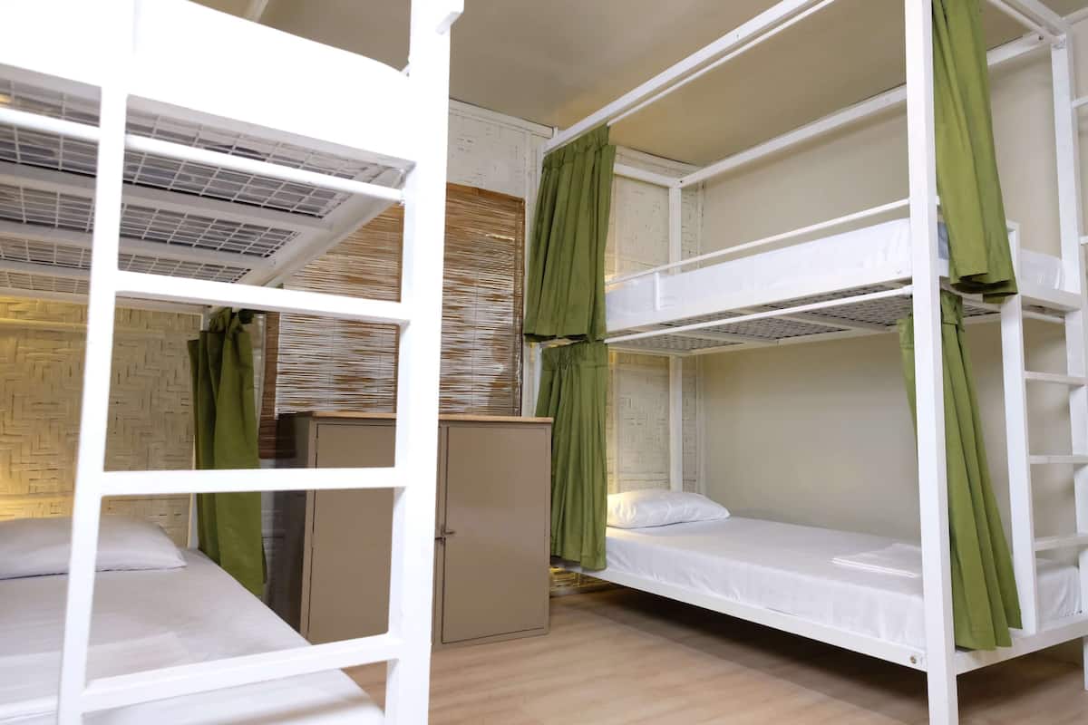 Quarto com beliche, cortinas verdes, guarda-roupa e parede com padrão losango.