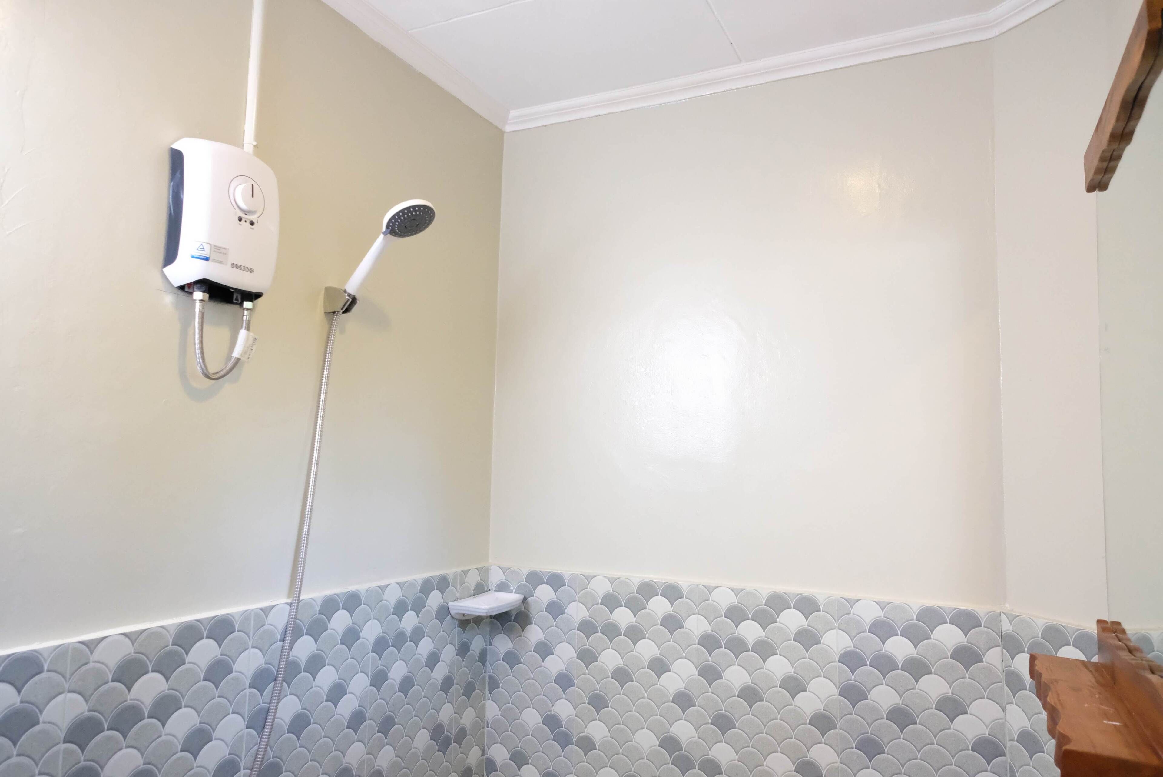 A bathroom with a shower, a wall-mounted water heater, and a tiled floor.