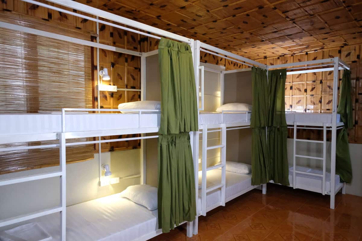 Quarto com beliches, paredes de madeira e chão ladrilhado.