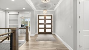 Un couloir avec un plancher en bois, une porte en verre et un luminaire.