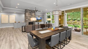 Un salon moderne comprenant un coin repas, une cheminée et une vue sur le jardin.